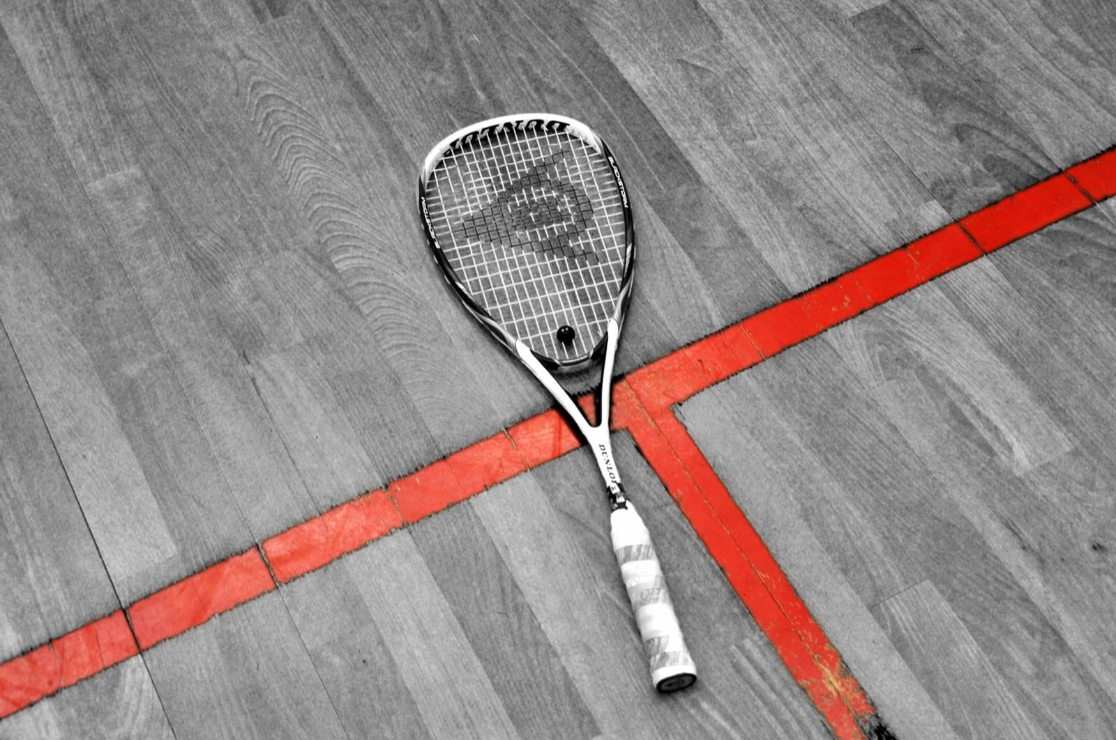 Squashschläger auf dem Parkett, an der roten Linie